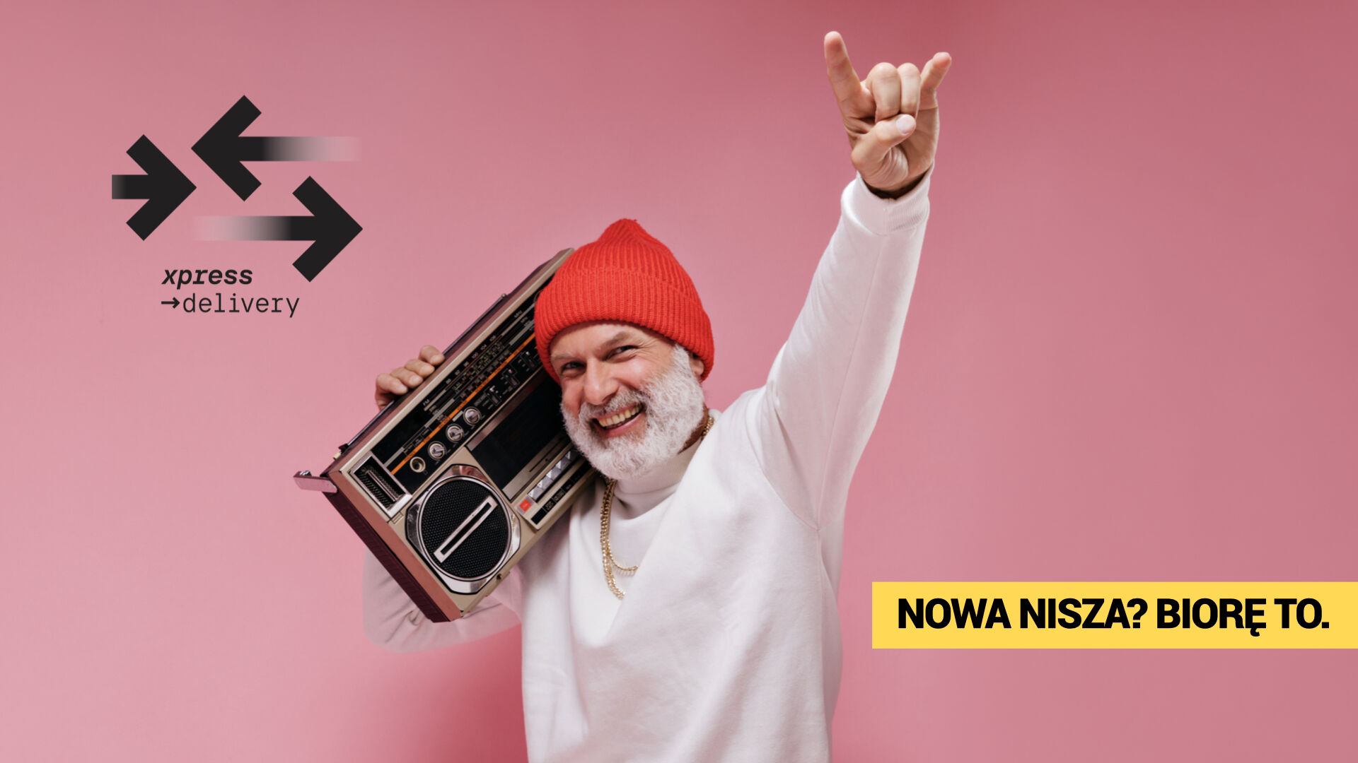 Uśmiechnięty mężczyzna w czerwonej czapce z boomboxem na tle różowego tła – ekspresowa dostawa produktów niszowych z Xpress Delivery. Hasło: „Nowa nisza? Biorę to.”